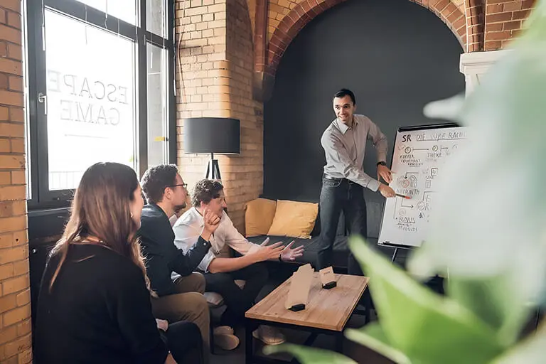 Person skizziert mit Marker ein Diagramm auf einem karierten Flipchart.